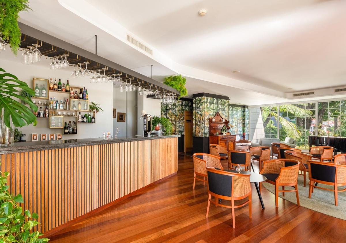 um restaurante com bar, mesas e cadeiras em Quintinha Sao Joao Hotel & Spa no Funchal