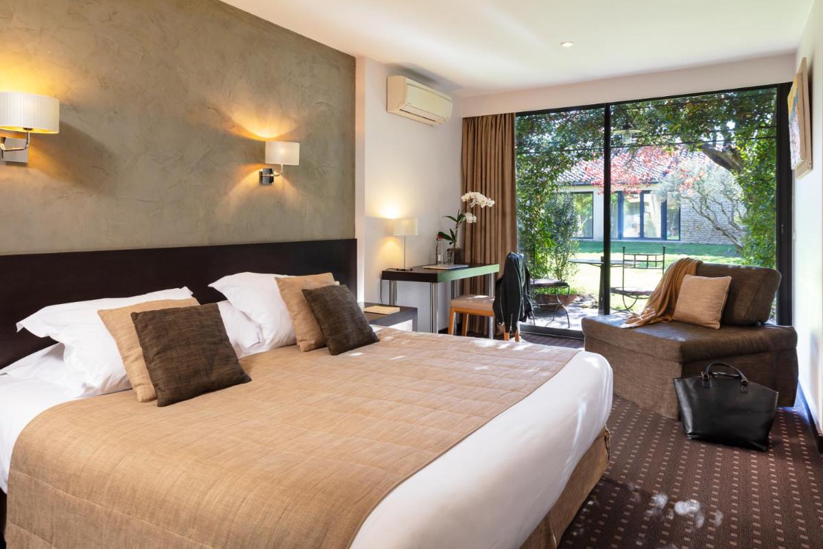 une chambre d'hôtel avec un grand lit et un bureau dans l'établissement Hôtel Carcarille Restaurant Le C, à Gordes