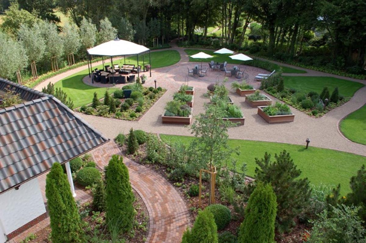 eine Luftansicht auf einen Garten mit Tischen und Sonnenschirmen in der Unterkunft Hotel Landhaus Wachtelhof in Rotenburg an der Wümme