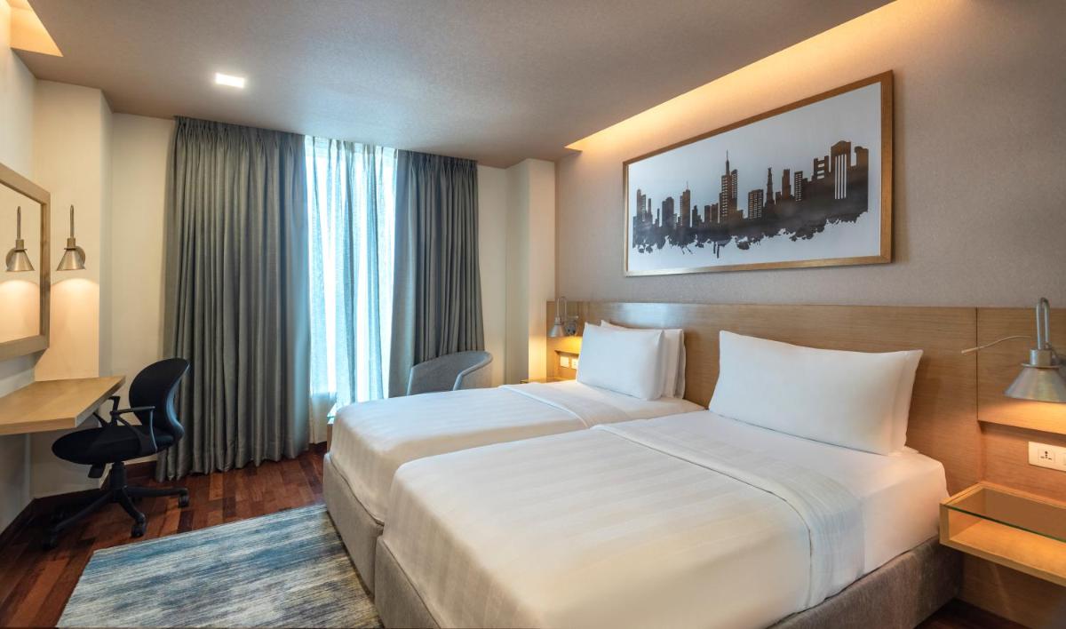 a hotel room with a large white bed and a desk at Radisson Gurugram Sohna Road City Center in Gurgaon a hotel room with a large white bed and a desk at Radisson Gurugram Sohna Road City Center in Gurgaon