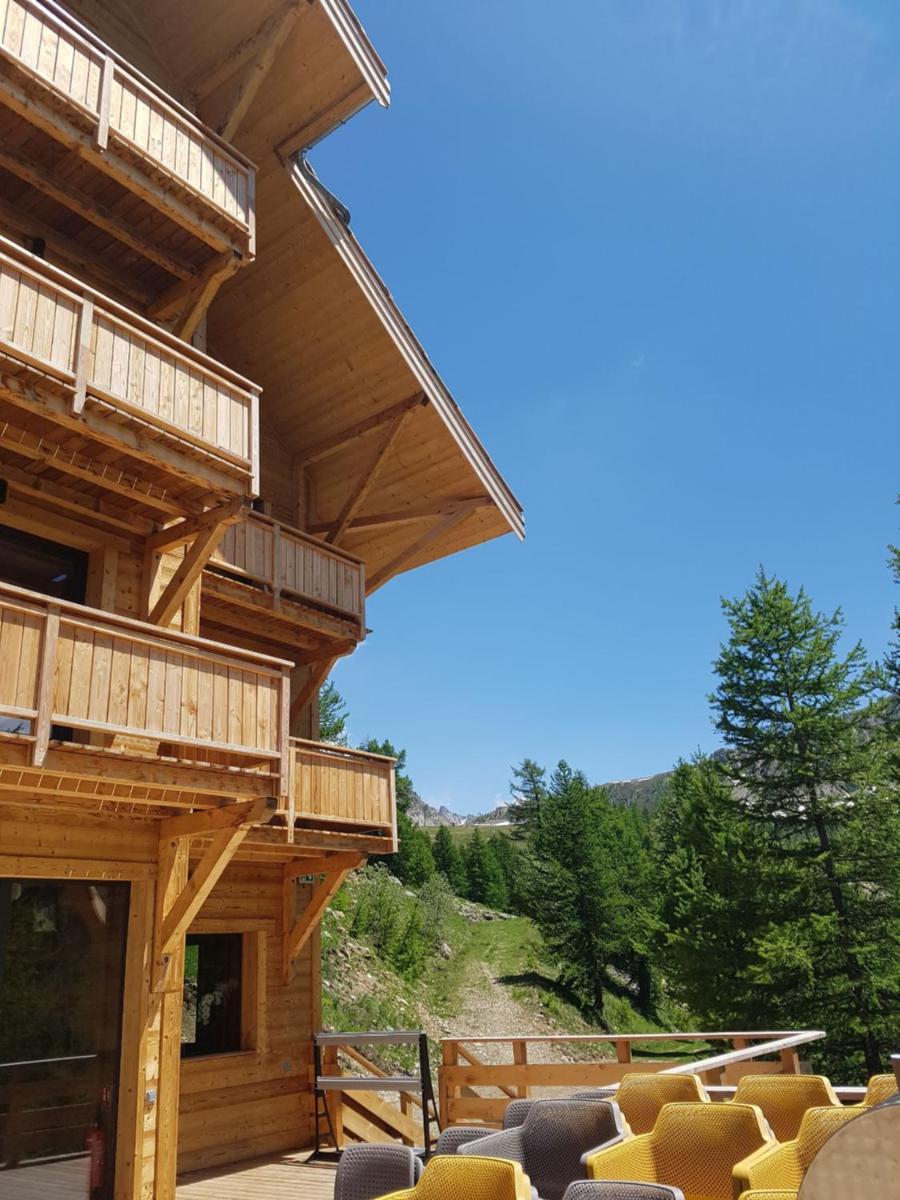 - un grand bâtiment en bois avec une terrasse et des chaises dans l'établissement Chalet Marano Restaurant & Spa, à Isola 2000