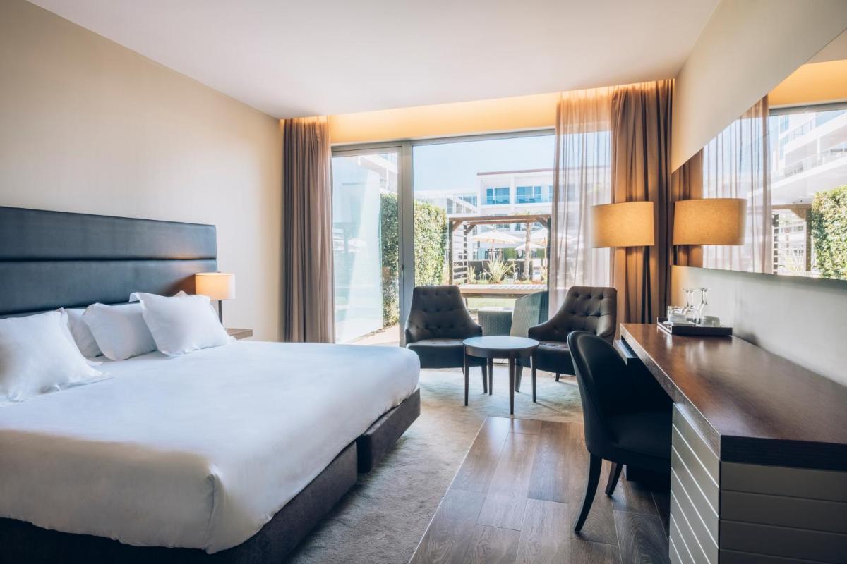 um quarto de hotel com uma cama, uma escrivaninha e cadeiras em Iberostar Selection Lagos Algarve em Lagos