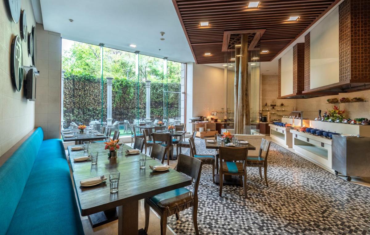 a restaurant with tables and chairs and a large window at Radisson Gurugram Sohna Road City Center in Gurgaon a restaurant with tables and chairs and a large window at Radisson Gurugram Sohna Road City Center in Gurgaon