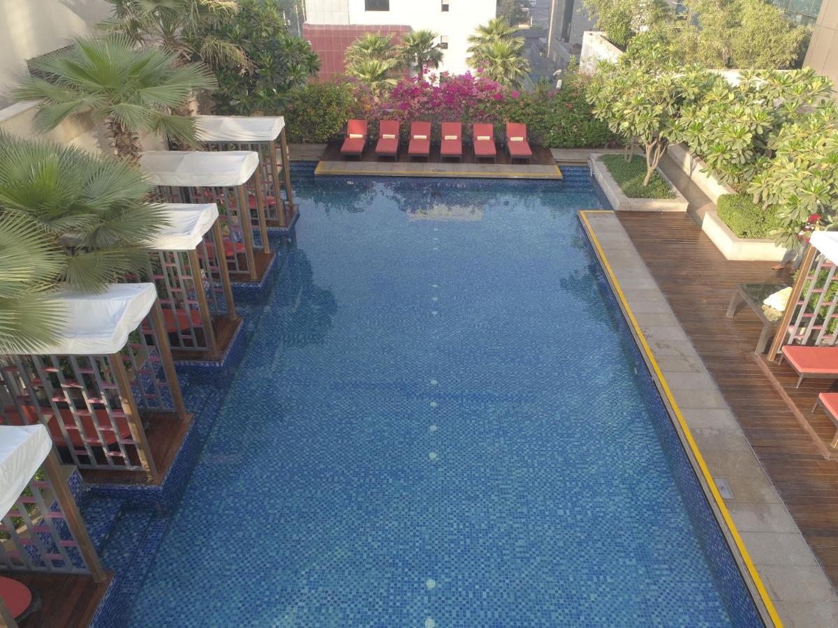 a swimming pool with chairs and blue water at Taj City Centre Gurugram in Gurgaon