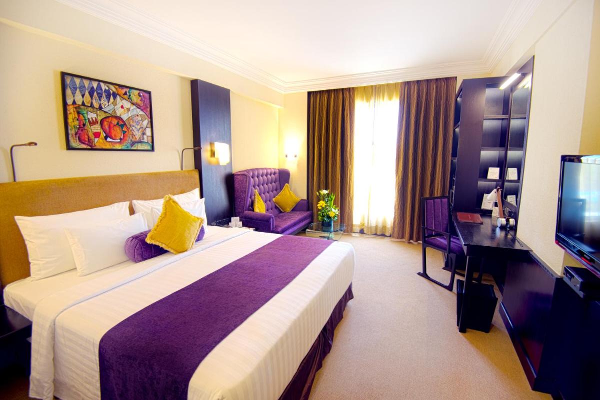 a hotel room with a bed and a television at Sterlings Mac Hotel in Bengaluru