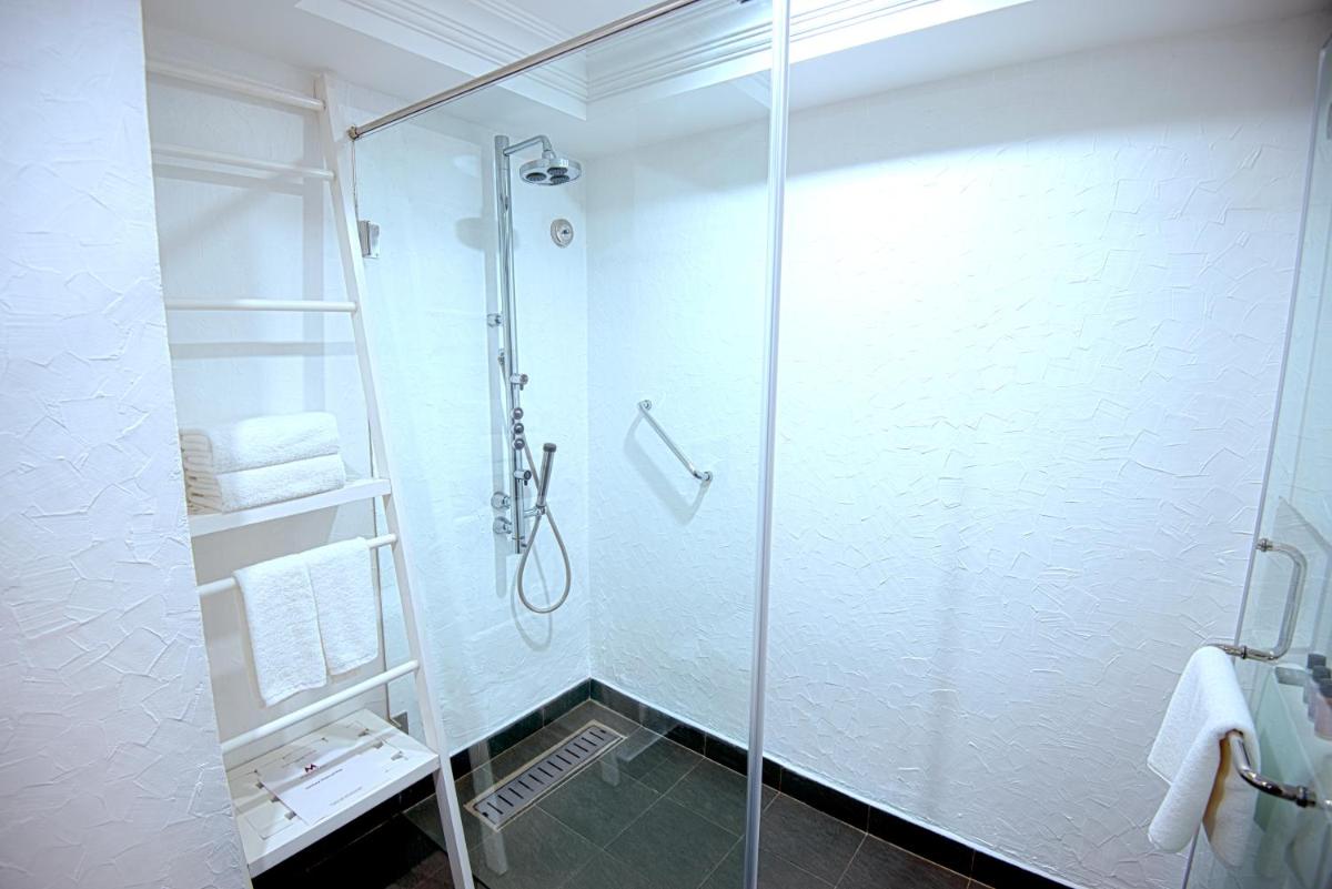 a shower with a glass door in a bathroom at Sterlings Mac Hotel in Bengaluru