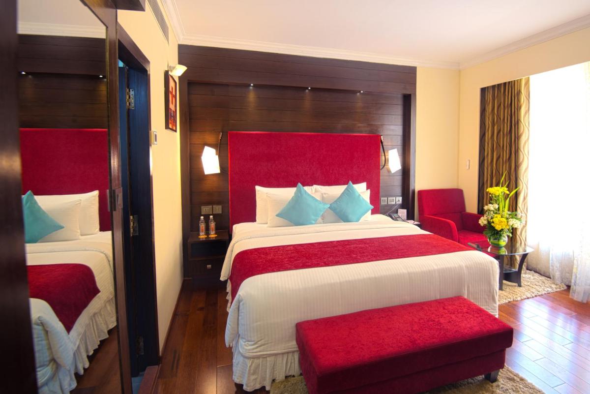 a bedroom with two beds and a red headboard at Sterlings Mac Hotel in Bengaluru