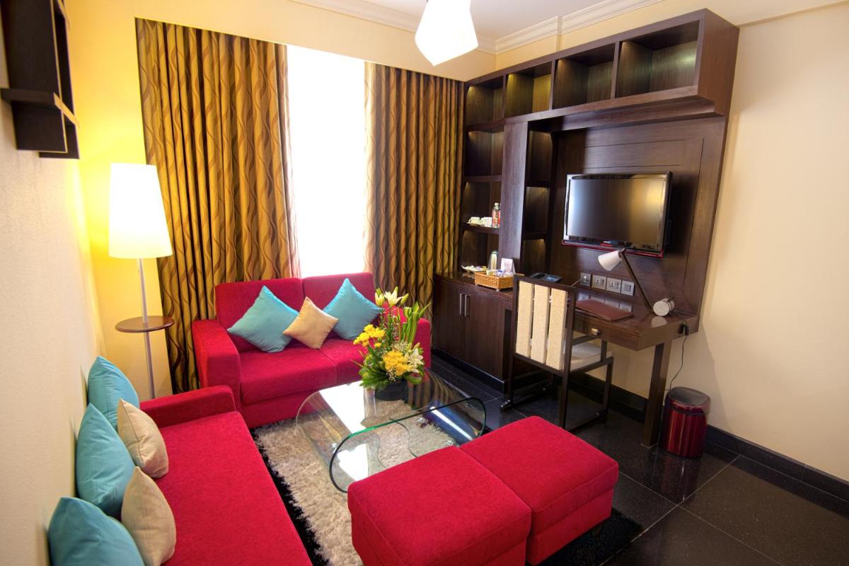 a living room with red furniture and a flat screen tv at Sterlings Mac Hotel in Bengaluru