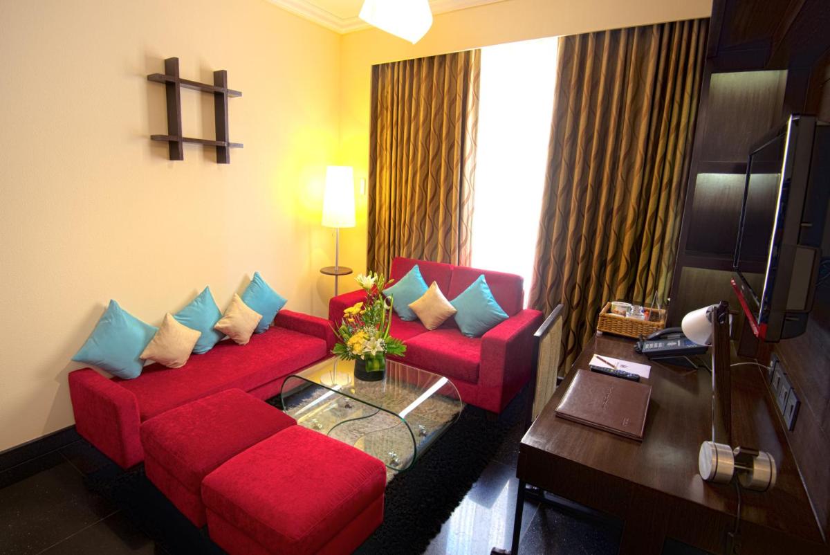a living room with a red couch and a table at Sterlings Mac Hotel in Bengaluru