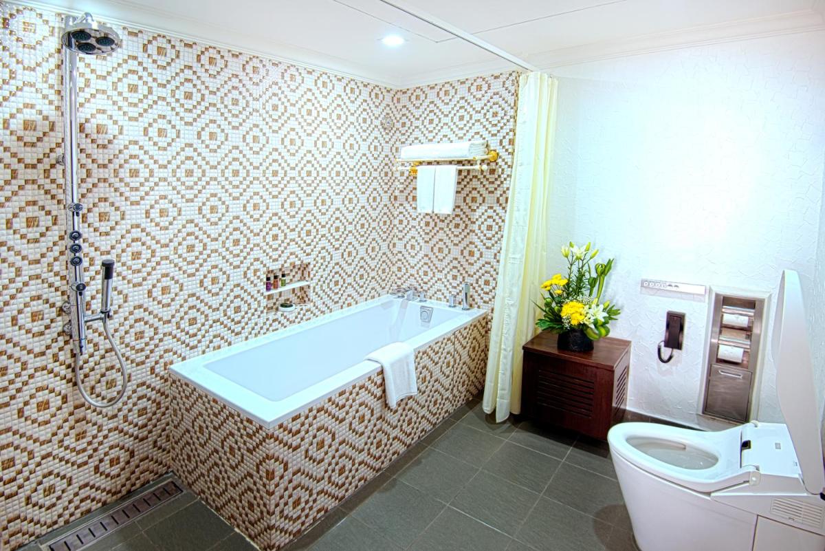 a bathroom with a bath tub and a toilet at Sterlings Mac Hotel in Bengaluru
