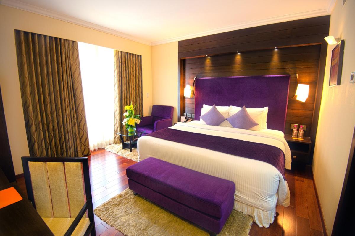 a bedroom with a large bed with a purple headboard at Sterlings Mac Hotel in Bengaluru