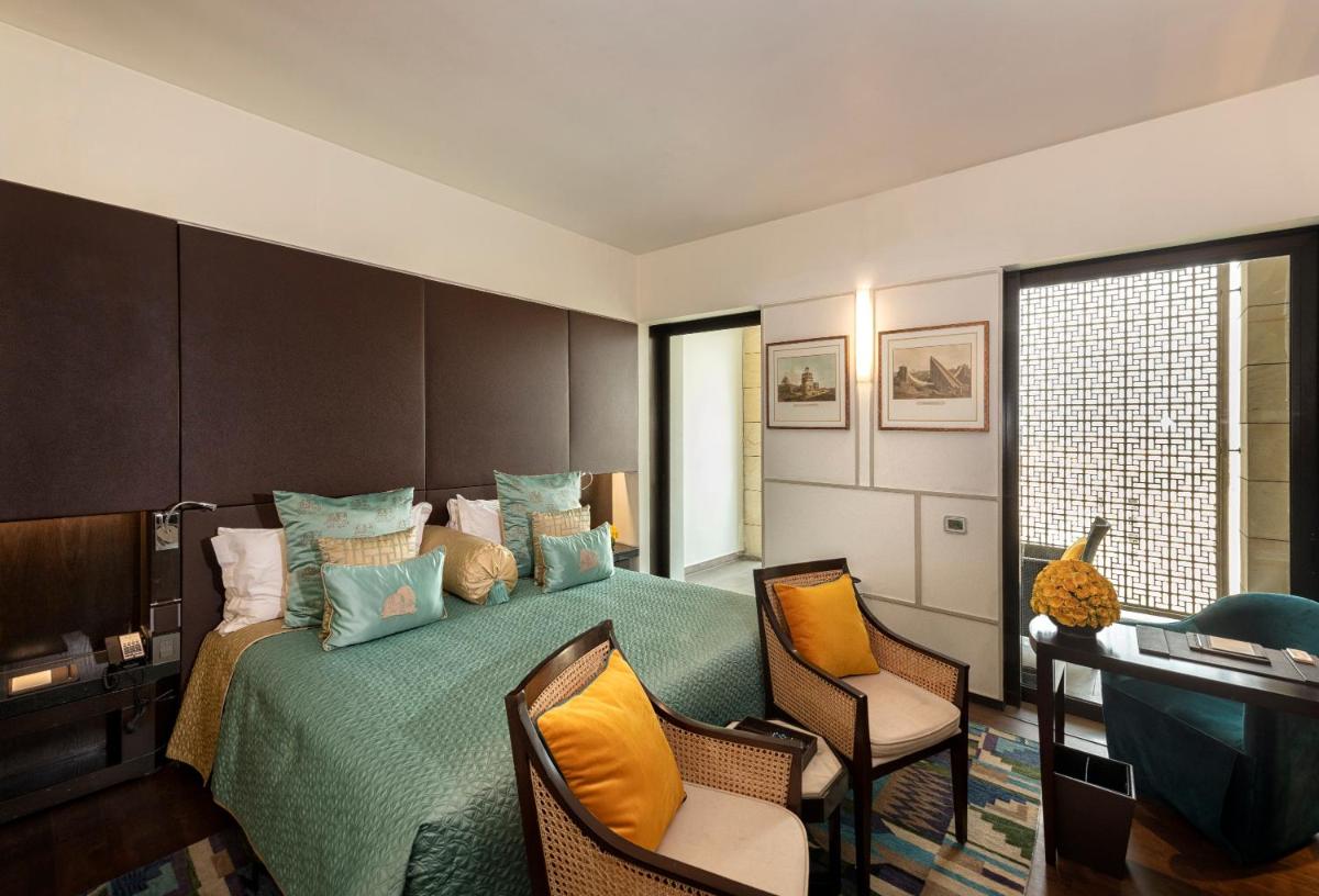 a bedroom with a green bed with two chairs at The Lodhi – A member of The Leading Hotels Of The World in New Delhi