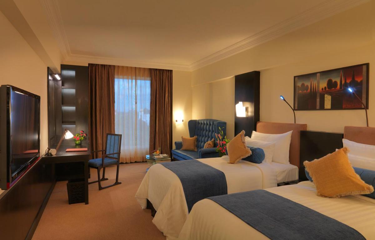 a hotel room with two beds and a television at Sterlings Mac Hotel in Bengaluru
