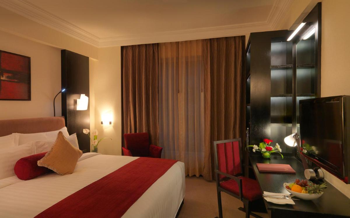 a hotel room with a bed and a television at Sterlings Mac Hotel in Bengaluru