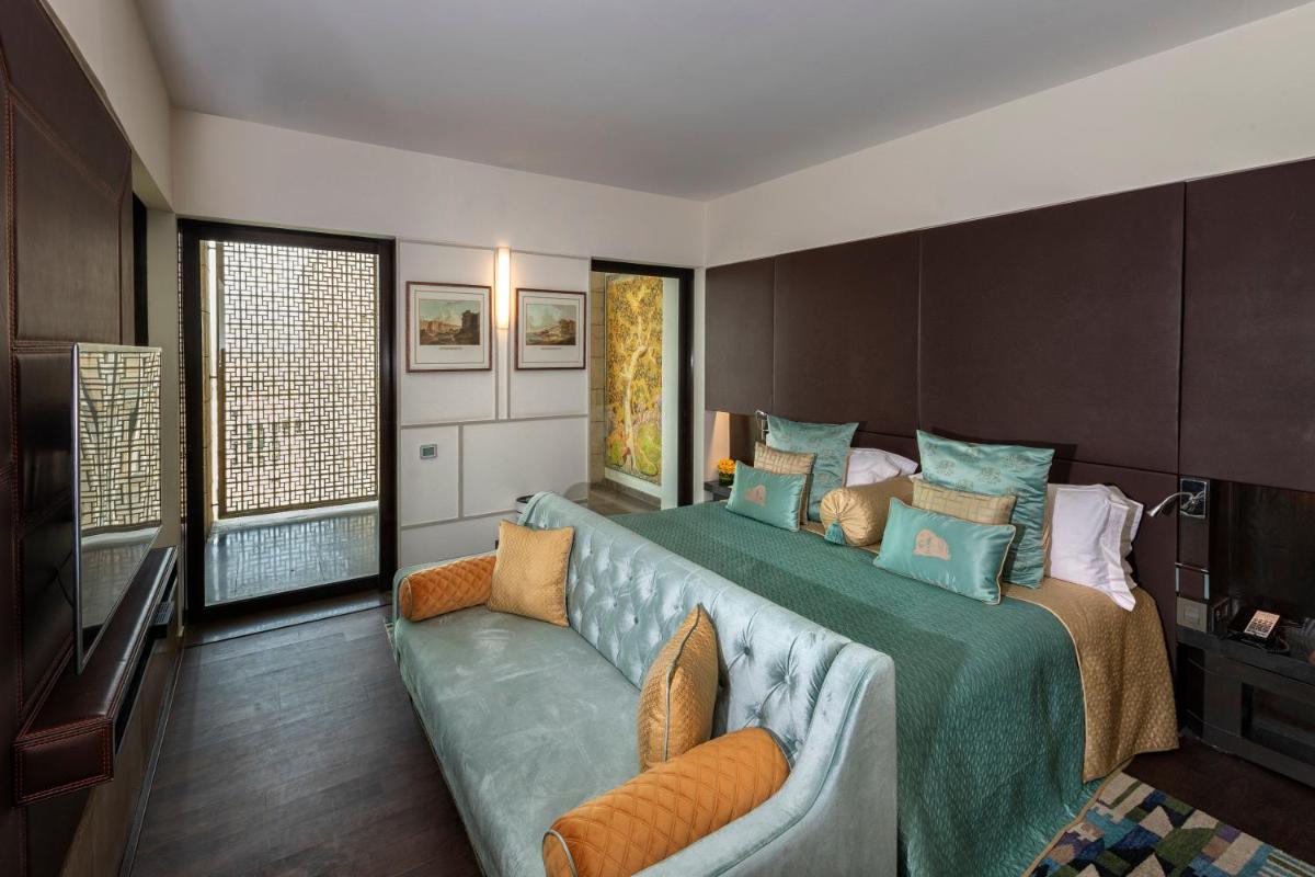 a bedroom with a large bed and a couch at The Lodhi – A member of The Leading Hotels Of The World in New Delhi