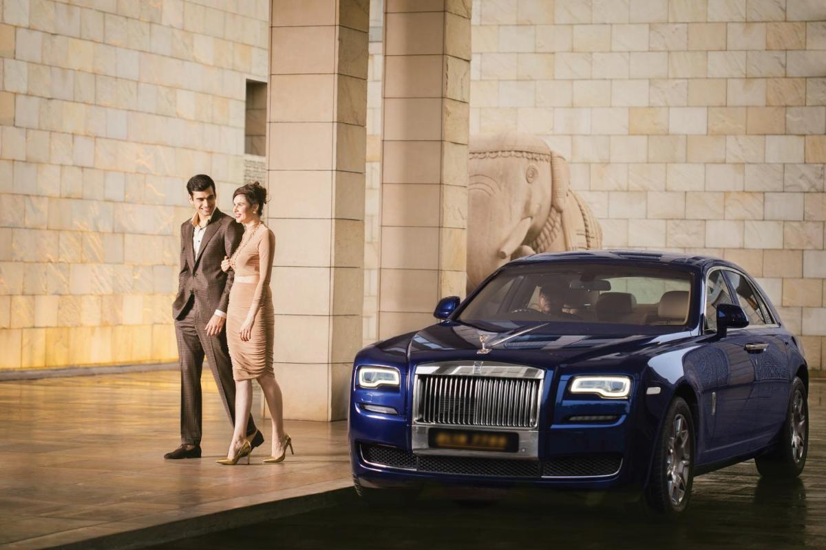 a man and a woman standing next to a blue car at The Lodhi – A member of The Leading Hotels Of The World in New Delhi