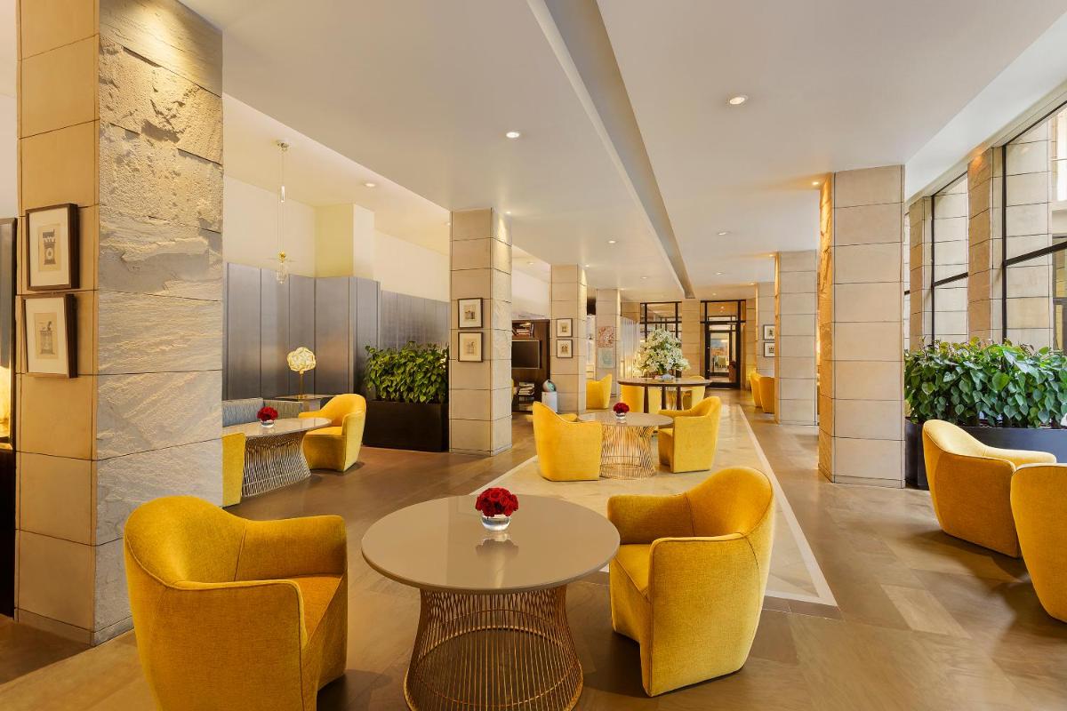 a lobby with yellow chairs and a table at The Lodhi – A member of The Leading Hotels Of The World in New Delhi