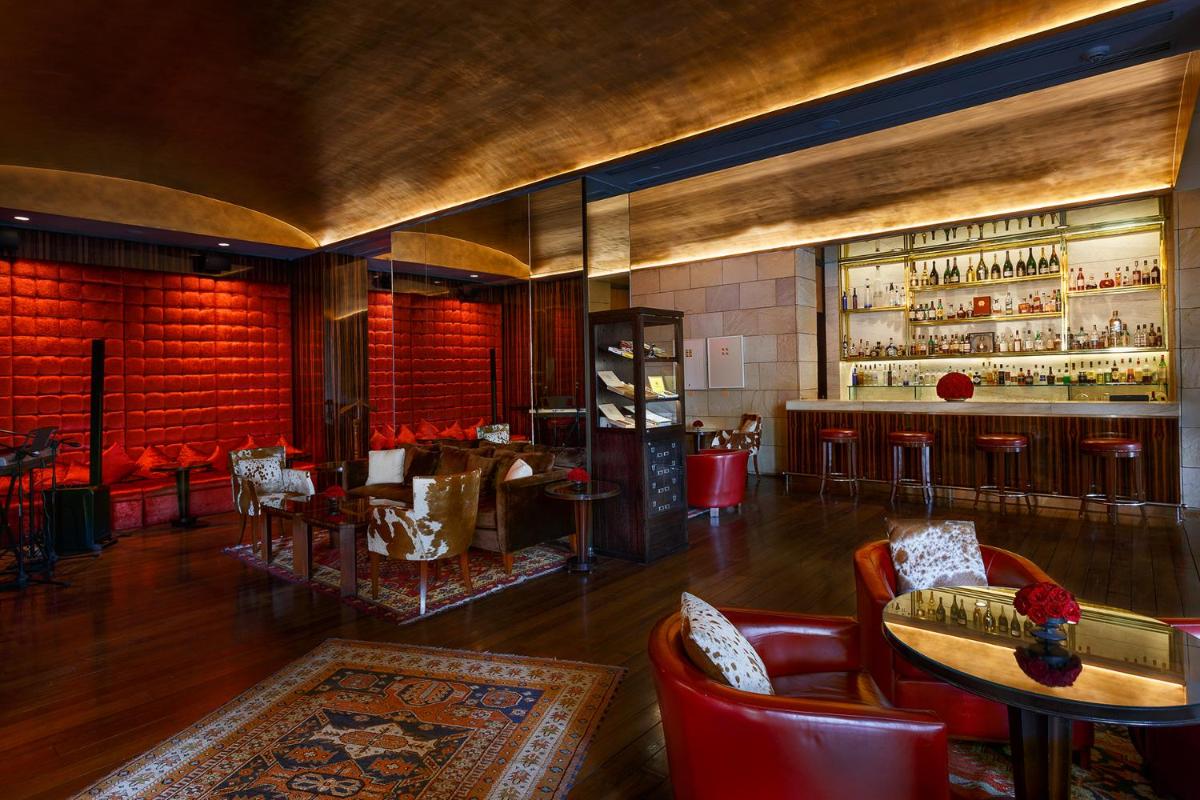 a restaurant with a bar with red chairs and tables at The Lodhi – A member of The Leading Hotels Of The World in New Delhi