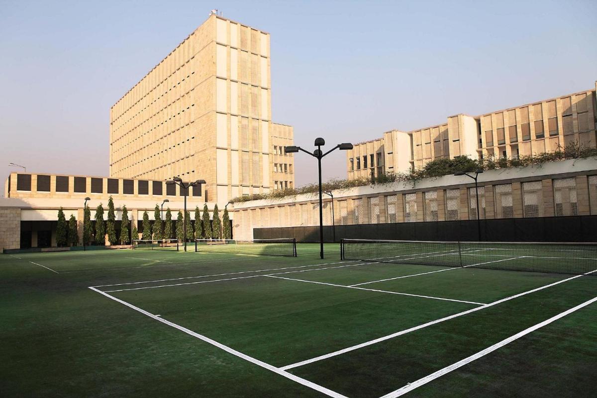 a tennis court in front of a large building at The Lodhi – A member of The Leading Hotels Of The World in New Delhi