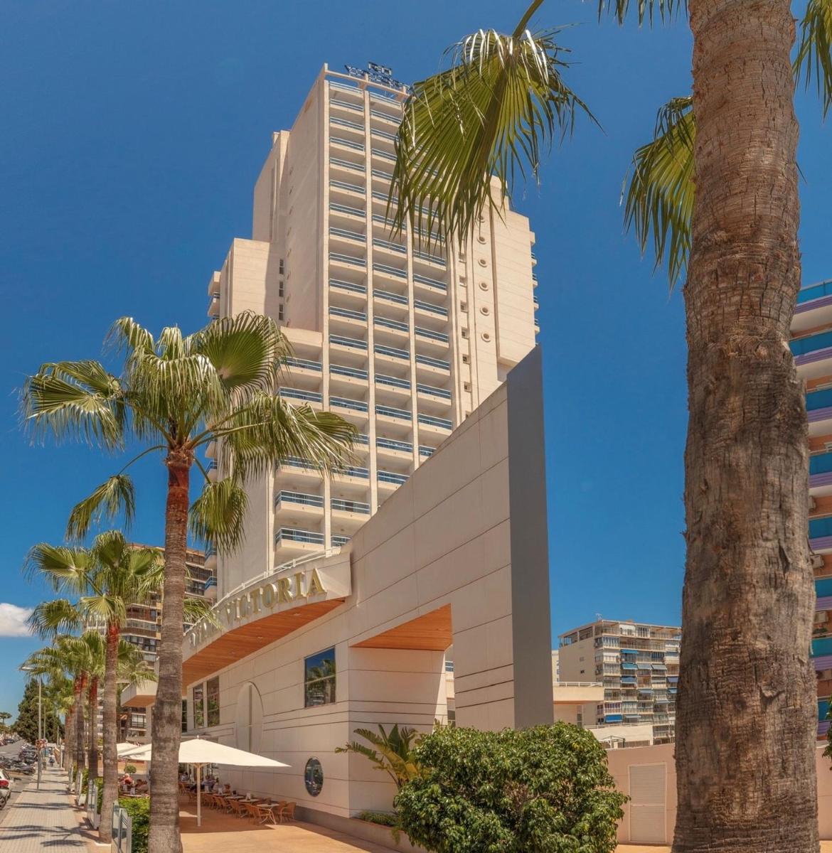 Un edificio alto con palmeras delante. en Hotel RH Victoria & Spa 4 Sup, en Benidorm