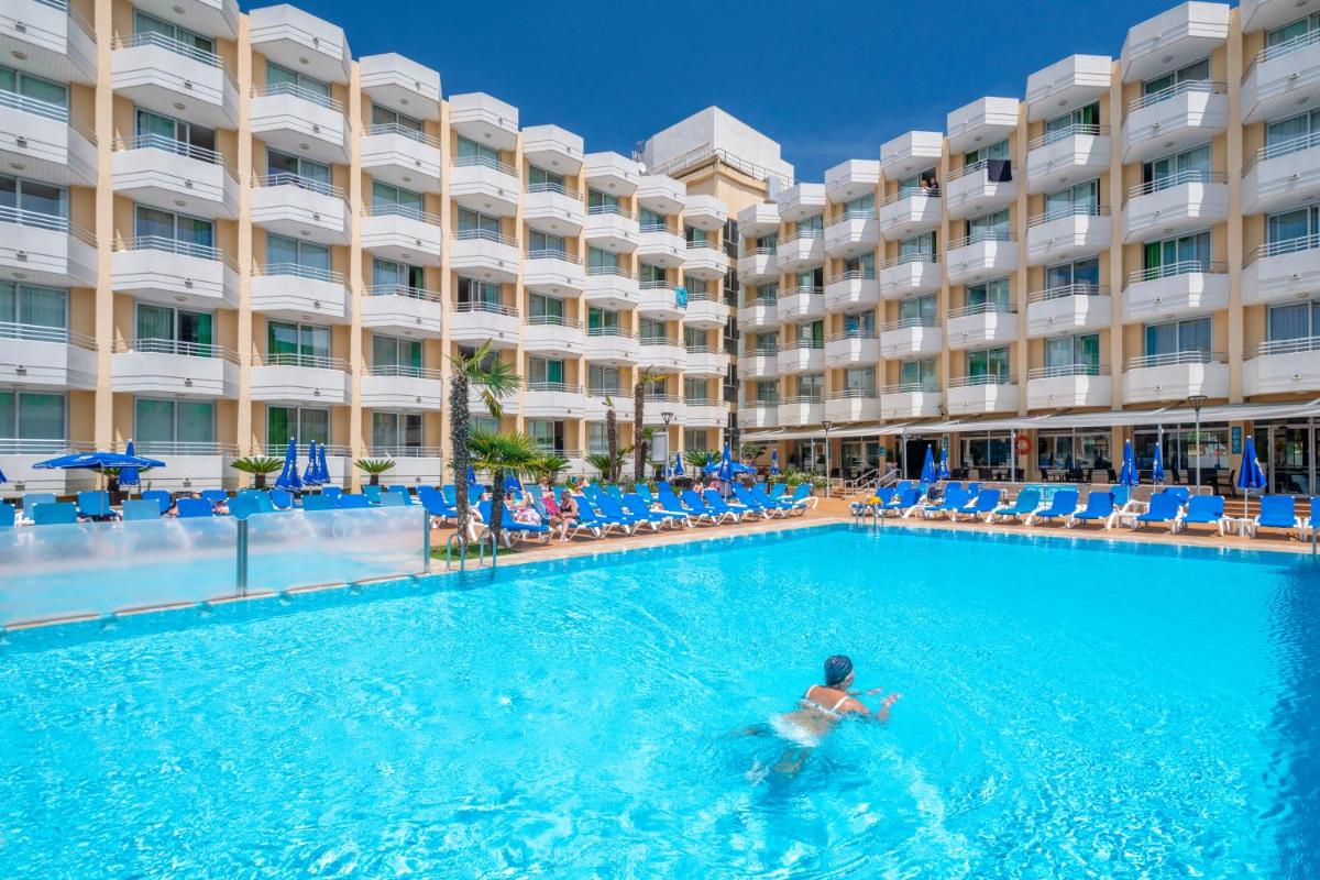 un hombre nadando en la piscina frente a un hotel en GHT Oasis Tossa & Spa, en Tossa de Mar