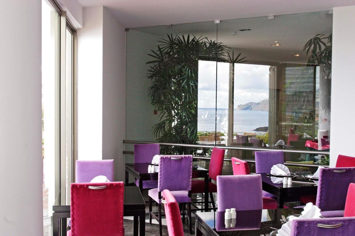 um restaurante com cadeiras roxas e vista para o oceano em Madeira Regency Cliff - Adults Only no Funchal