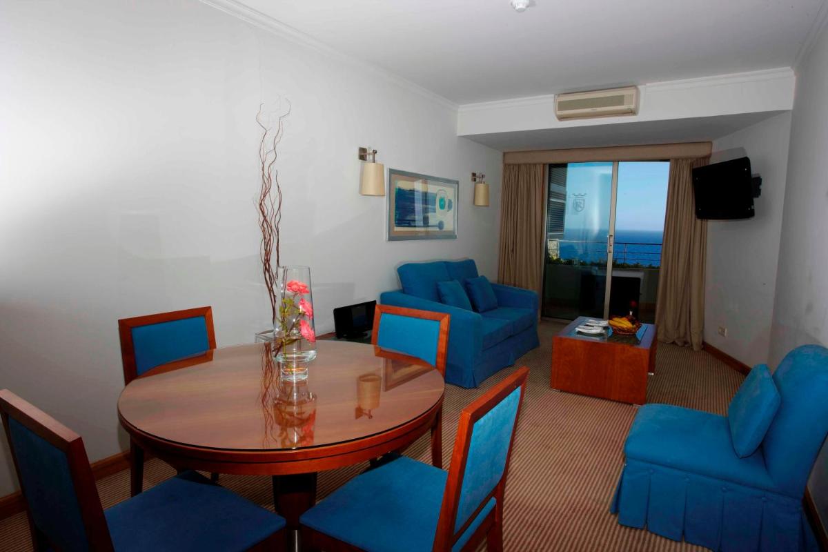 uma sala de estar com uma mesa e cadeiras azuis em Madeira Regency Cliff - Adults Only no Funchal