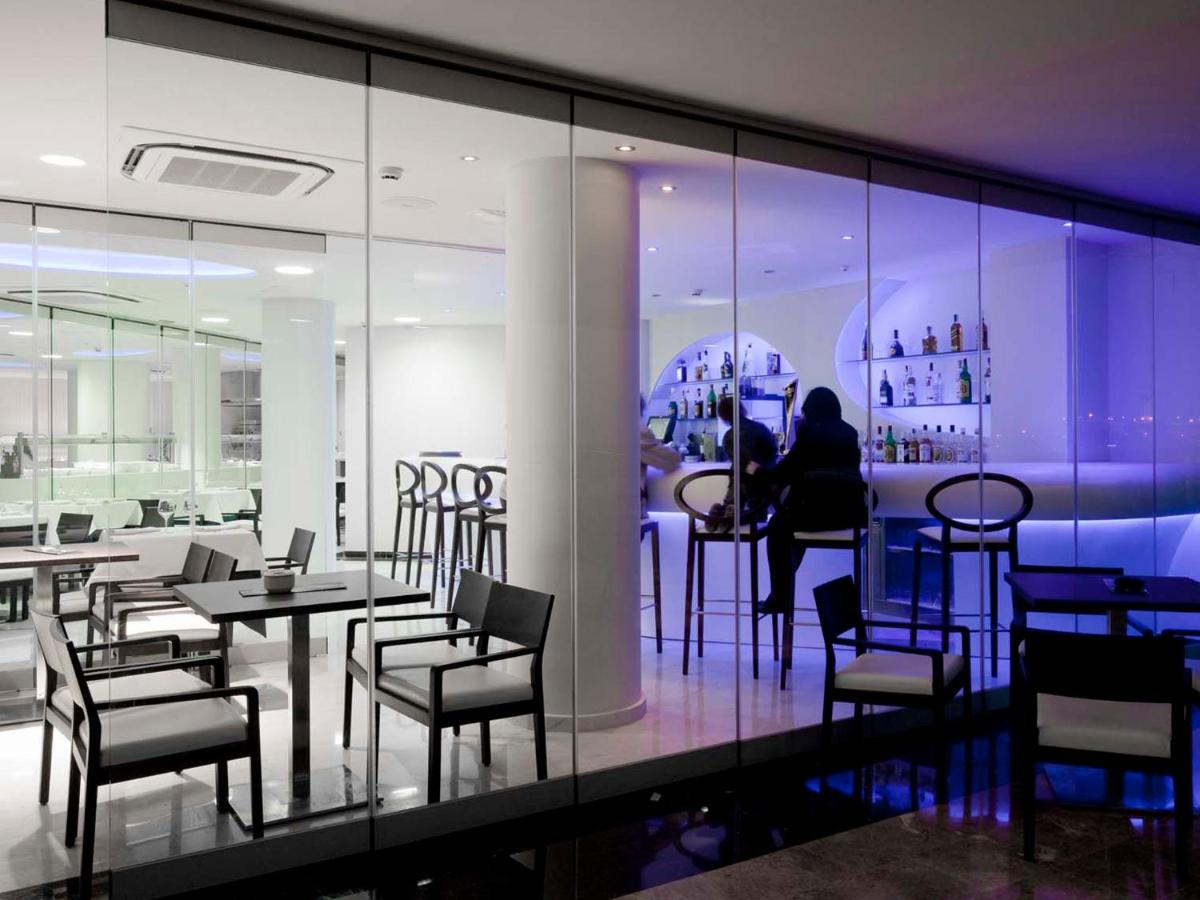 Un restaurante con sillas y mesas y un bar. en Hotel Villa del Mar, en Benidorm