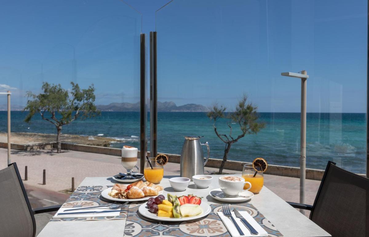 Una mesa con comida de desayuno y vista al océano. en Ferrer Concord Hotel & Spa, en Can Picafort