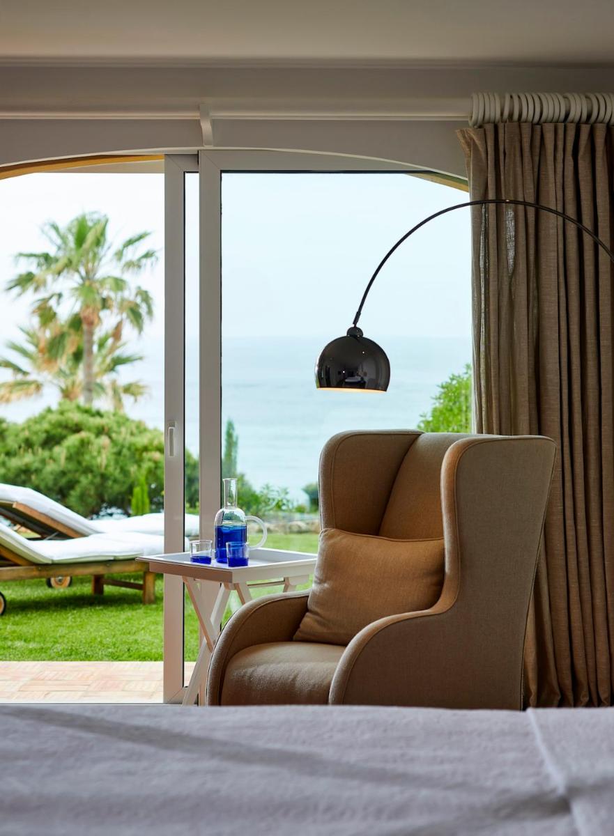 um quarto com uma cadeira e vista para o oceano em Vila Joya em Albufeira um quarto com uma cadeira e vista para o oceano em Vila Joya em Albufeira