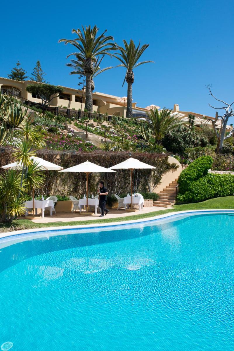 uma pessoa ao lado de uma piscina com palmeiras em Vila Joya em Albufeira