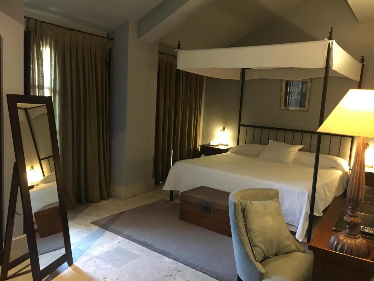 Un dormitorio con una cama con dosel y una silla. en Hotel Palacio de Mengibar, en Mengíbar 33 fotos más