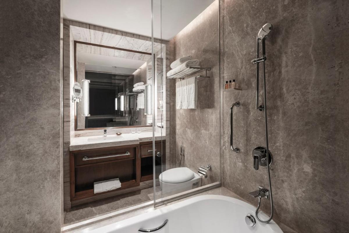 a bathroom with a tub and a sink and a shower at Shangri-La Eros New Delhi in New Delhi a bathroom with a tub and a sink and a shower at Shangri-La Eros New Delhi in New Delhi