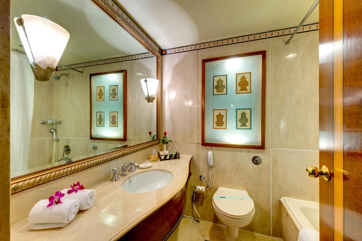 a bathroom with a sink and a toilet and a mirror at Hotel Hindusthan International, Kolkata in Kolkata