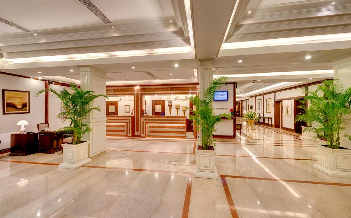 a lobby with two potted plants in a building at Hotel Hindusthan International, Kolkata in Kolkata