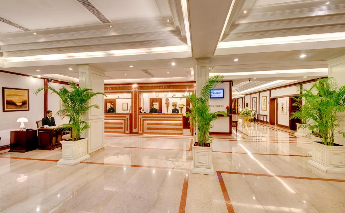 a lobby with potted plants and a man sitting at a desk at Hotel Hindusthan International, Kolkata in Kolkata +36 photos