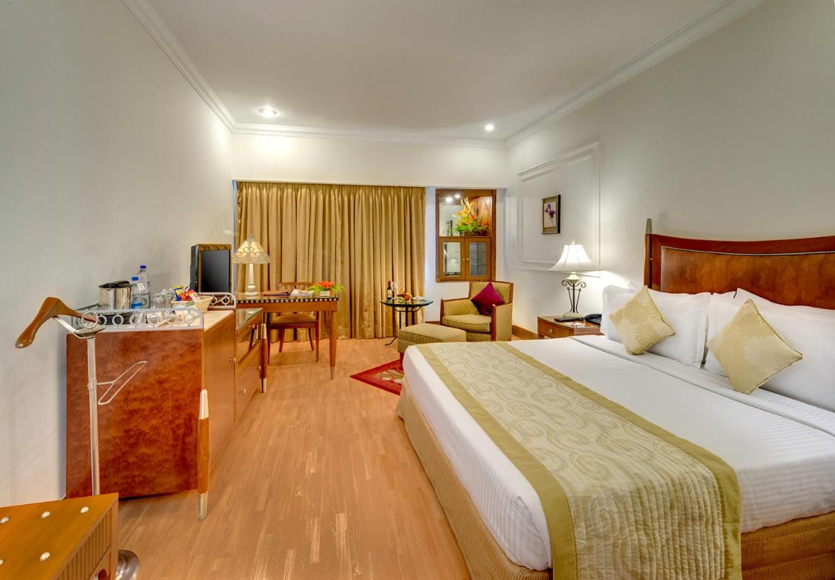 a hotel room with a large bed and a desk at Hotel Hindusthan International, Kolkata in Kolkata a hotel room with a large bed and a desk at Hotel Hindusthan International, Kolkata in Kolkata