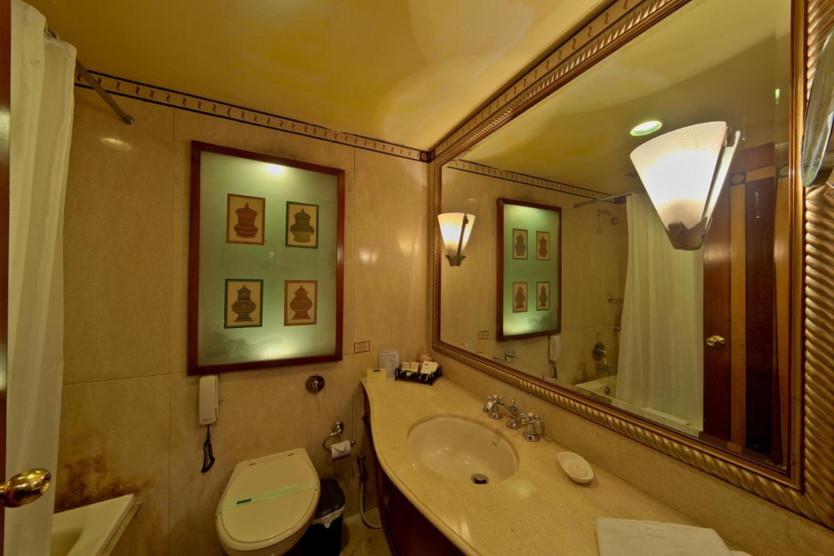 a bathroom with a sink and a toilet and a mirror at Hotel Hindusthan International, Kolkata in Kolkata