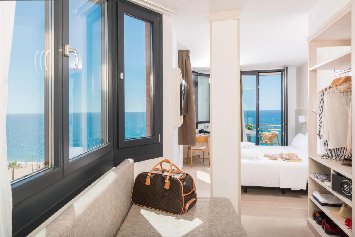 Habitación de hotel con sofá y dormitorio con vistas al océano en Hotel Marsol, en Lloret de Mar