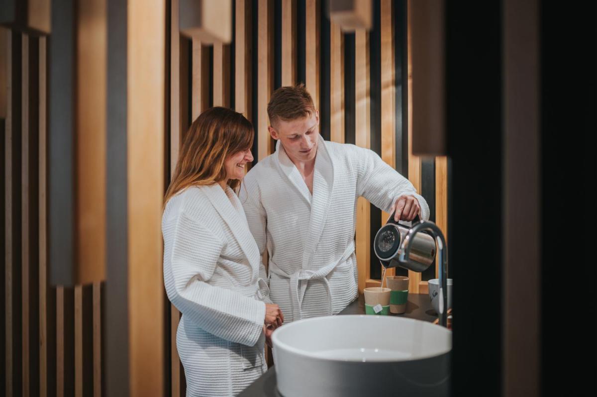 un homme et une femme debout à côté d'un évier dans l'établissement Logis Hôtel de la Tour, à Ribeauvillé