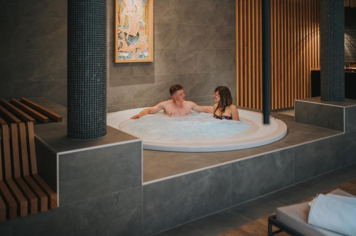 un homme et une femme dans un jacuzzi dans l'établissement Logis Hôtel de la Tour, à Ribeauvillé