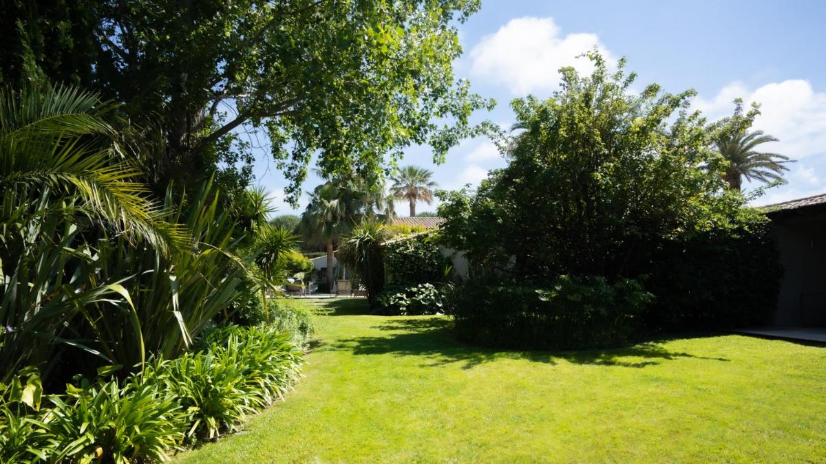 un jardin avec de l'herbe verte et des arbres et une maison dans l'établissement Le Pre de la Mer, à Saint-Tropez