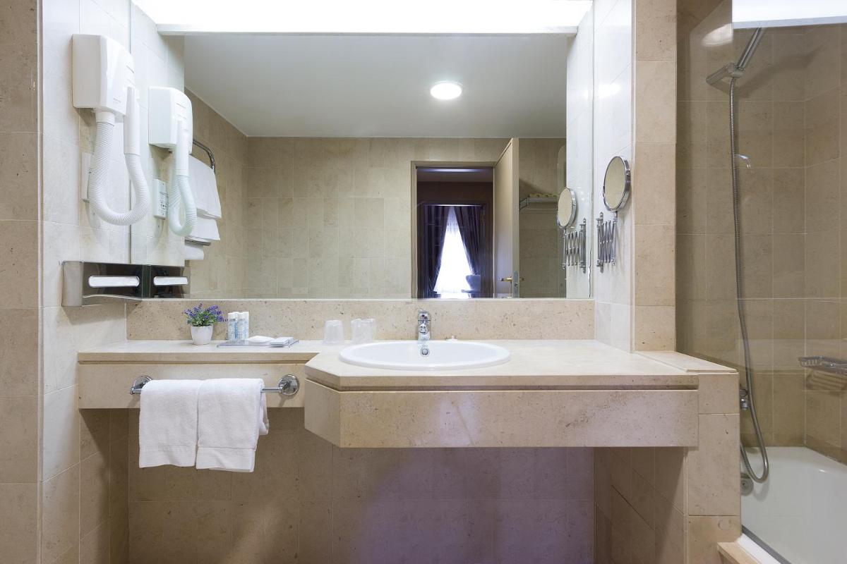 um banheiro com uma pia, um chuveiro e um espelho em Hotel Meira em Vila Praia de Âncora