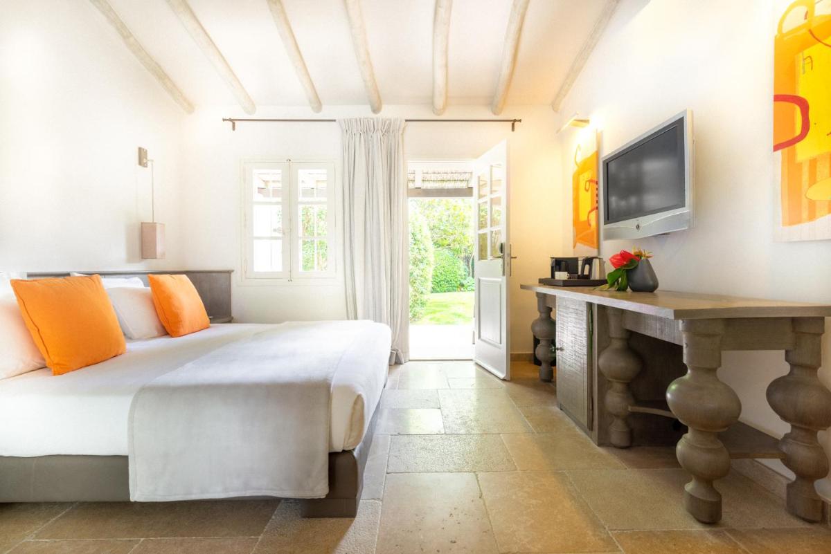 une chambre avec un lit, un bureau et une télévision dans l'établissement Le Pre de la Mer, à Saint-Tropez
