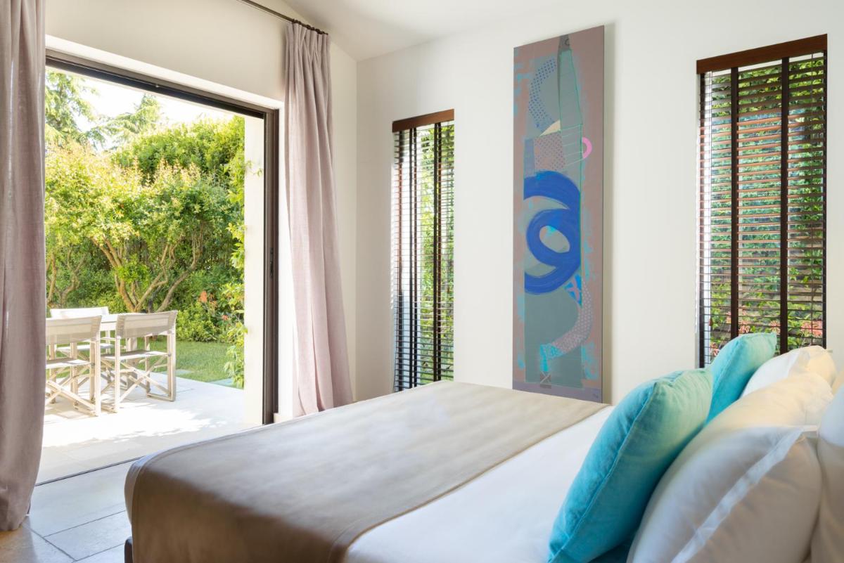 une chambre avec un lit et une grande fenêtre dans l'établissement Le Pre de la Mer, à Saint-Tropez