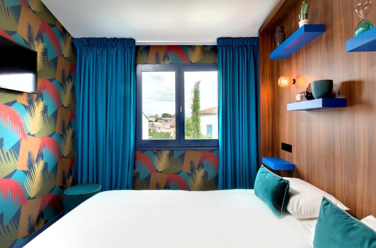 une chambre avec un lit et une fenêtre avec des rideaux bleus dans l'établissement Hôtel Montmorency & Spa, à Carcassonne