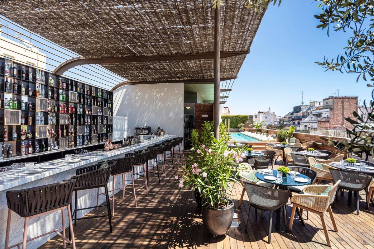 un restaurante con barra con mesas y sillas en Sir Victor Hotel, part of Sircle Collection, en Barcelona un restaurante con barra con mesas y sillas en Sir Victor Hotel, part of Sircle Collection, en Barcelona