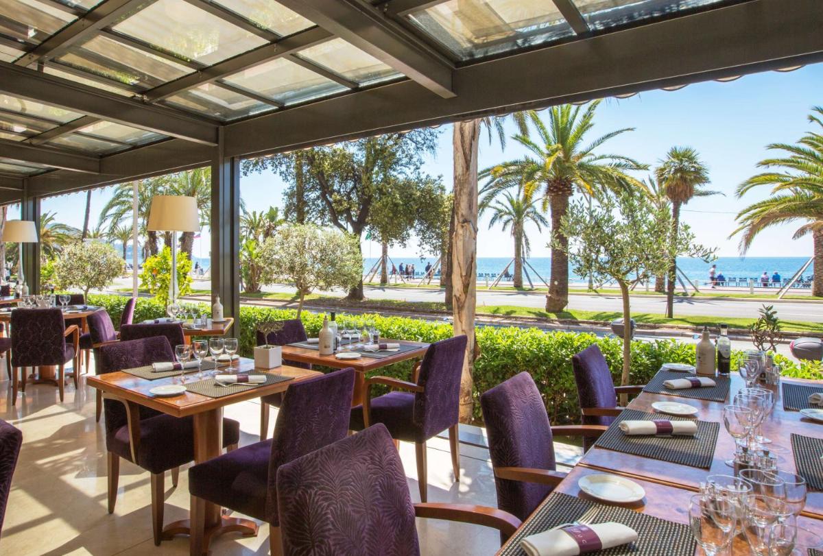 un restaurant avec des tables et des chaises avec l'océan en arrière-plan dans l'établissement Westminster Hotel & Spa Nice, à Nice