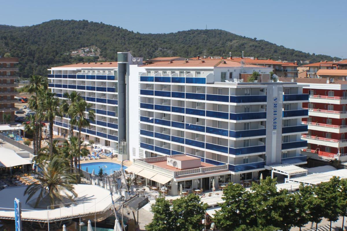 Un gran edificio blanco con una piscina enfrente. en Hotel Riviera, en Santa Susanna Un gran edificio blanco con una piscina enfrente. en Hotel Riviera, en Santa Susanna