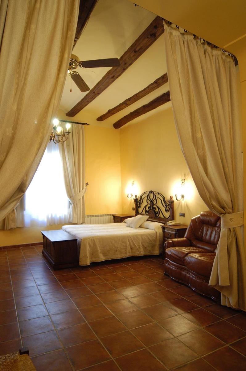 Un dormitorio con una cama y un sofá y una ventana. en Hotel SPA Don Iñigo de Aragón, en Las Cuevas de Cañart